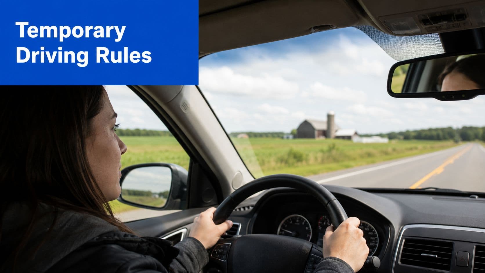 A female driver looking ahead while holding the steering wheel of a car on a rural road.