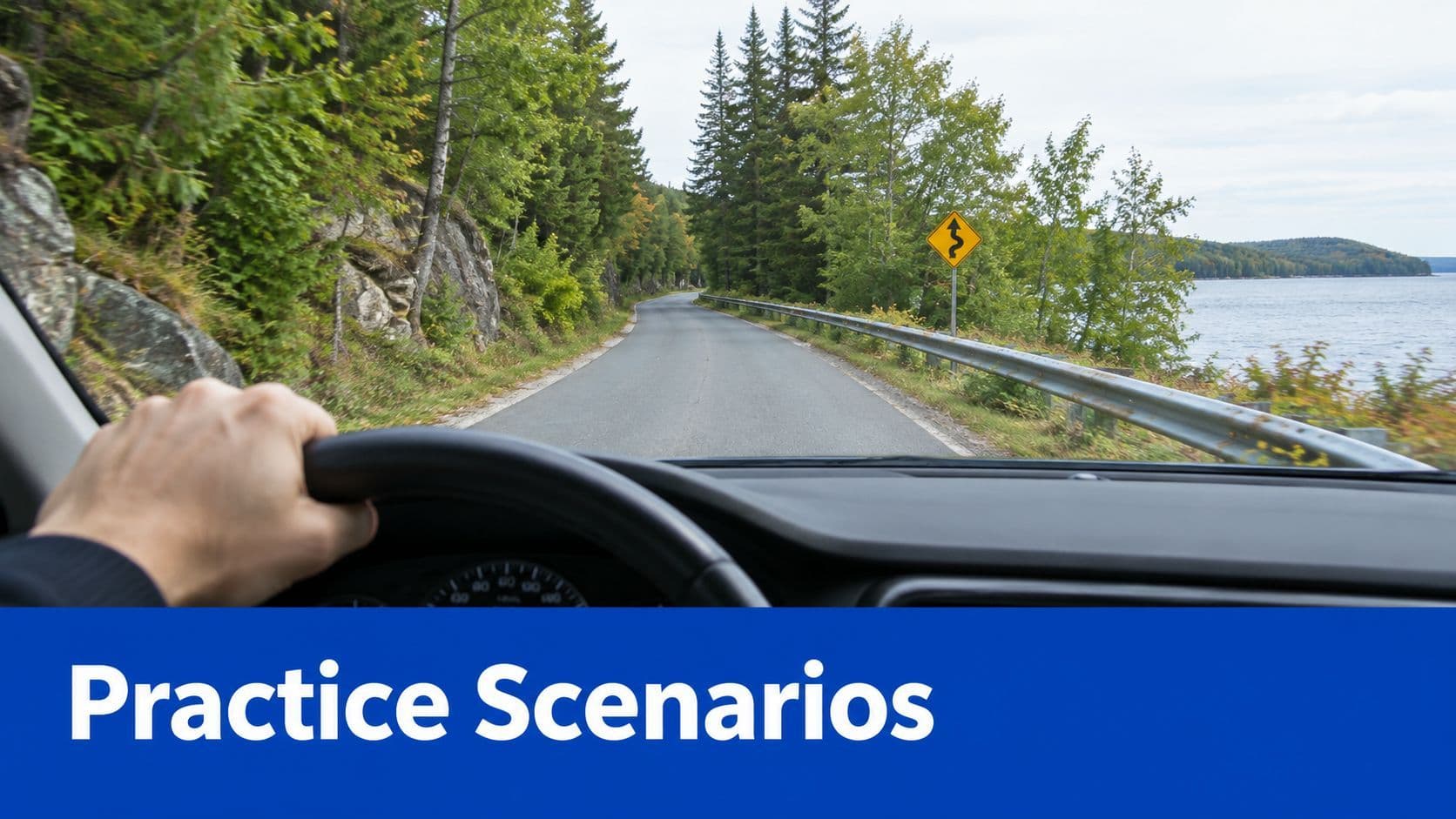 A driver's view from inside a car traveling on a winding road next to a large lake.
