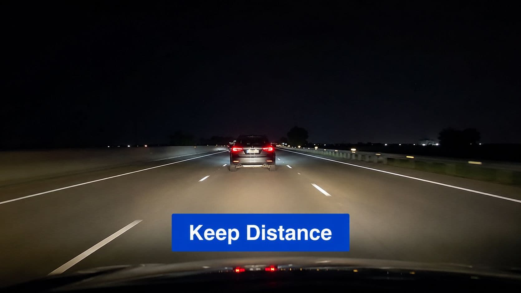 A view from inside a car driving on a highway at night behind another vehicle.