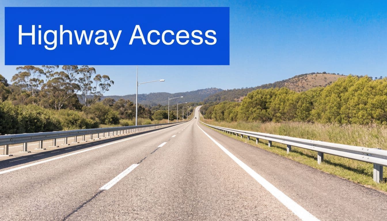 A straight highway road stretching toward distant rolling hills under a clear blue sky.