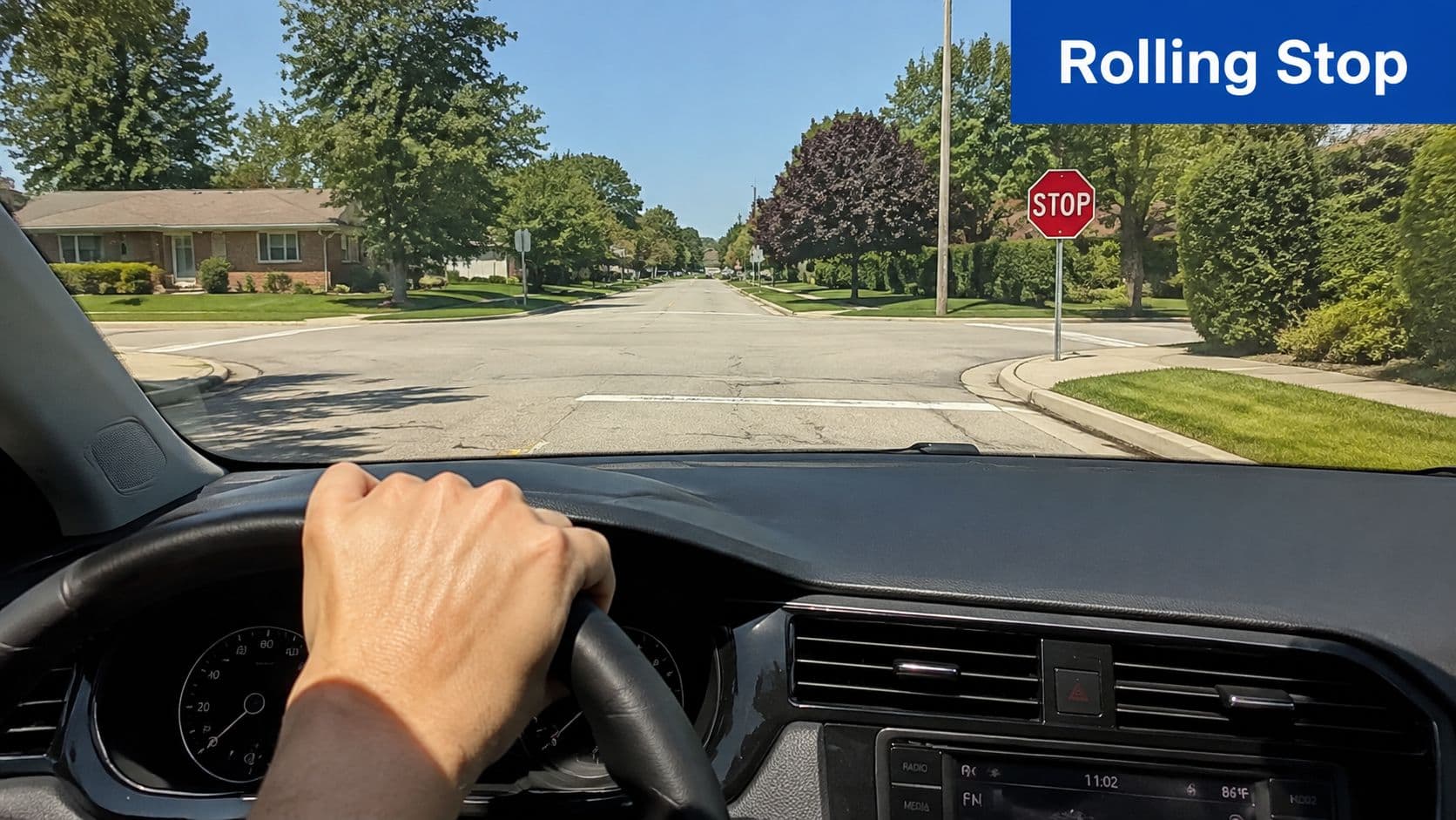 A driver's perspective from inside a car approaching a stop sign on a suburban residential street.